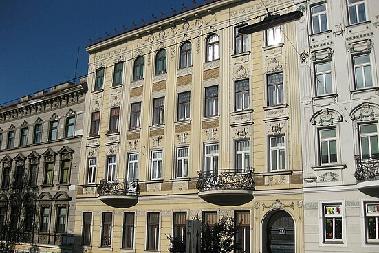 Beiger Altbau mit runden Balkonen